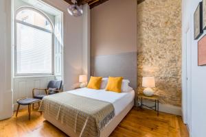 a bedroom with a bed and two chairs and a window at Bacharéis Charming House in Figueira da Foz