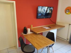 uma mesa e cadeiras com uma televisão na parede em Zimmerappartement "Rose" - Ferienwohnungen Wagner & Gaul em Falkenauel