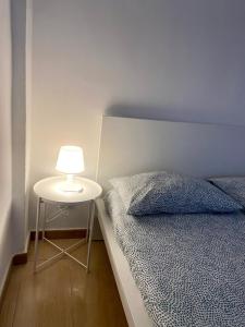 a bed and a table with a lamp next to it at Morosini 11 in Turin