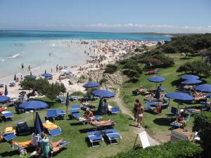 a group of people on a beach with blue umbrellas at Residence Hotel La Pelosetta in Stintino