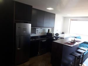 a kitchen with black cabinets and a white refrigerator at Maravilhoso Apto Vista Mar Jacuzzi Wi Fi Pé Areia in Santos