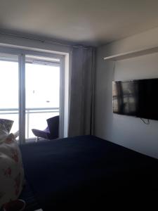 um quarto com uma cama, uma televisão e uma janela em Maravilhoso Apto Vista Mar Jacuzzi Wi Fi Pé Areia em Santos