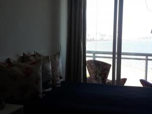 a bedroom with a bed with pillows and a window at Maravilhoso Apto Vista Mar Jacuzzi Wi Fi Pé Areia in Santos