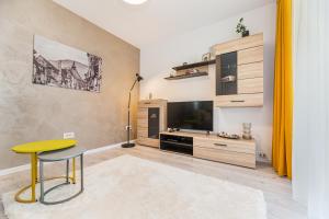 een woonkamer met een gele kruk en een televisie bij RentForComfort Apartment Ella 2 in Braşov