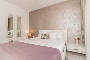 een slaapkamer met een groot wit bed en een muur bij RentForComfort Apartment Ella 2 in Braşov