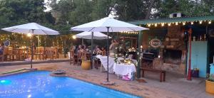 a restaurant with tables and umbrellas next to a pool at Rosenhof Studio Five - When Privacy is Important in Clanwilliam