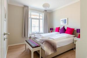 una camera da letto con un grande letto bianco con cuscini rosa di Stadthaus Brüggemann a Husum
