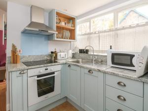 cocina con armarios blancos, fregadero y microondas en Verdi en Pitlochry