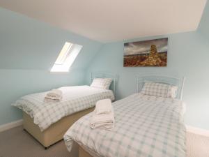 2 camas individuales en una habitación con paredes azules en Puccini en Pitlochry