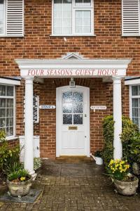 uma porta da frente de uma casa de tijolos com uma casa de hóspedes de quatro estações em All Seasons Gatwick Guest House & Parking em Horley