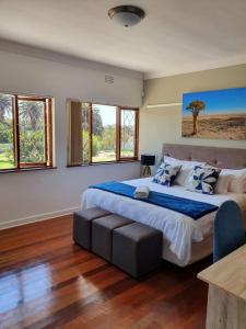 a bedroom with a large bed with a table and windows at Avanti Guest Lodge in Vredenburg
