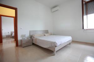ein weißes Schlafzimmer mit einem Bett und einem Fenster in der Unterkunft Villa Cecita in Sellia Marina
