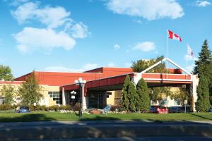 a large building with a red roof and a flag at Canad Inns Destination Centre Garden City in Winnipeg