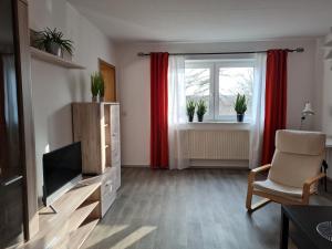 ein Wohnzimmer mit einem TV, einem Stuhl und einem Fenster in der Unterkunft Ferienwohnung Schloss Burgk in Burgk