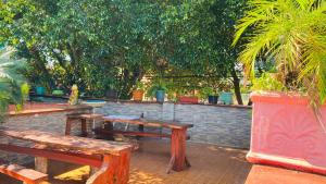 zwei Holzbänke neben einer Ziegelwand mit Bäumen in der Unterkunft Mario Algarin in Puerto Iguazú