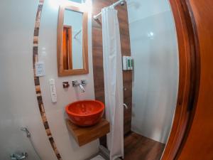 uma casa de banho com um lavatório vermelho e um espelho. em Hotel Cuatro Pinos em Oberá