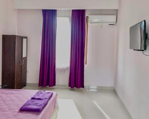 沙马林达Tiara Guest House Samarinda RedPartner的带紫色床和窗户的卧室