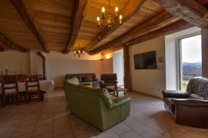 a living room with couches and a television and a table at Gîtes du Chênelong Cantal in Marchastel