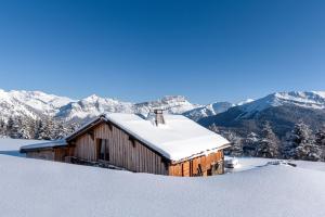a barn covered in snow with mountains in the background at Chalet De Praz Dru in Les Houches