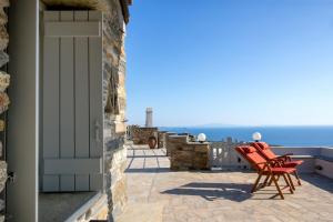 a pair of red chairs sitting on a balcony overlooking the ocean at Villa Adele in Arnados
