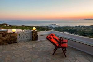 a red chair sitting on a balcony with the sunset at Villa Adele in Arnados