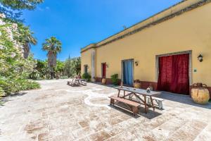 eine Terrasse mit zwei Picknicktischen vor einem Gebäude in der Unterkunft Le Palmentelle - Masseria con piscina in San Cesario di Lecce