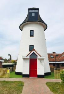 un phare avec une porte rouge au milieu dans l'établissement De Lievensmolen, à Damme