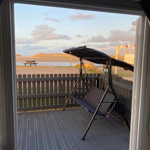 a chair on a porch with a view of the beach at Beachfront Lodge, Lossiemouth Bay in Lossiemouth
