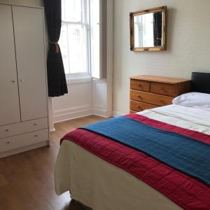 Schlafzimmer mit einem Bett, einer Kommode und einem Spiegel in der Unterkunft Apartment Newington Area in Edinburgh