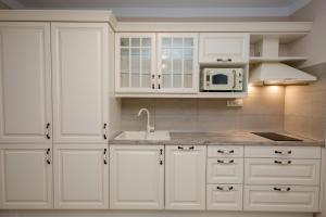 a kitchen with white cabinets and a sink and a microwave at Villa Luka Lopar in Lopar
