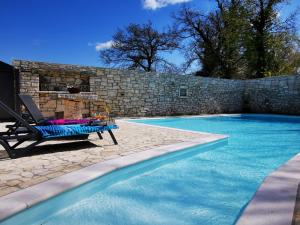 una piscina con una silla junto a una pared de piedra en Casa della Grofica en Kringa