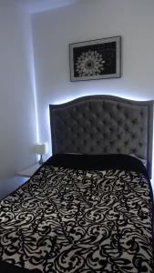 a bedroom with a bed with a black and white bedspread at Apartament Neon in Gdynia