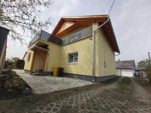 una casa amarilla con techo de gambrel en Duma Home en Balatonkeresztúr