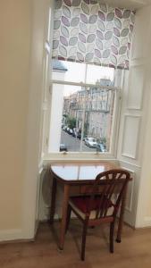 a table and a chair in front of a window at Apartment Newington Area in Edinburgh