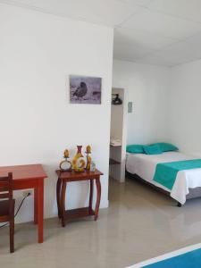 um quarto com uma cama, uma mesa e uma cama em Hostal Los Flamencos em Puerto Villamil