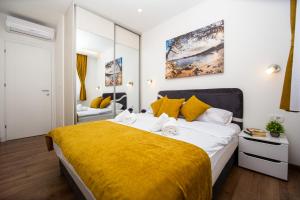 a bedroom with a large bed with a yellow blanket at Milara Apartments in Budva