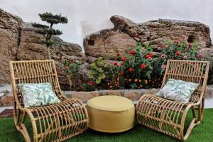 two chairs and a ottoman in front of a flower garden at Villa Tauria- Casa de campo em aldeia medieval in Sabugal