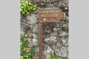 a sign in front of a stone wall at Villa Tauria- Casa de campo em aldeia medieval in Sabugal