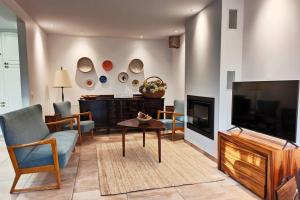 a living room with a tv and a couch and a table at Villa Tauria- Casa de campo em aldeia medieval in Sabugal