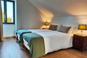 a bedroom with two beds and two lamps on tables at Villa Tauria- Casa de campo em aldeia medieval in Sabugal