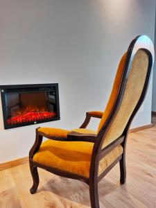 a chair in a living room with a fireplace at Villa Tauria- Casa de campo em aldeia medieval in Sabugal