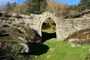 an old stone bridge with an arch over a river at Villa Tauria- Casa de campo em aldeia medieval in Sabugal