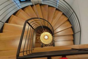 a spiral staircase with a gold chandelier at Villa Tauria- Casa de campo em aldeia medieval in Sabugal