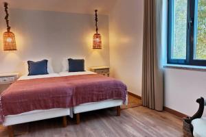 a bedroom with a bed with blue pillows and a window at Villa Tauria- Casa de campo em aldeia medieval in Sabugal