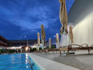 a pool with chairs and umbrellas next to a building at WhiteHouse in Popeşti-Leordeni