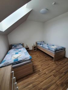 two beds in a room with wooden floors and ceilings at Penzion Amalka Dobříkov in Dobříkov