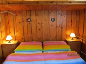 un letto in una camera con pareti in legno e 2 lampade di Horská chata Vlasta a Rokytnice nad Jizerou