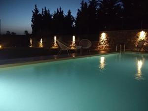 a swimming pool at night with chairs and lights at Alex House in Zakharo
