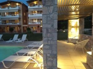 a patio with white lounge chairs and a building at Alex House in Zacharo