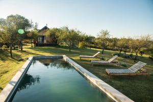 a swimming pool with two benches and a house at Finca Granero in Potrero de Garay